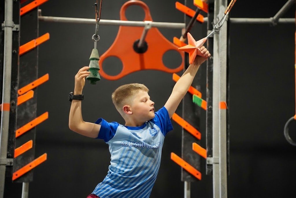 Boy reaching for the next obstacle at AWF Ninja