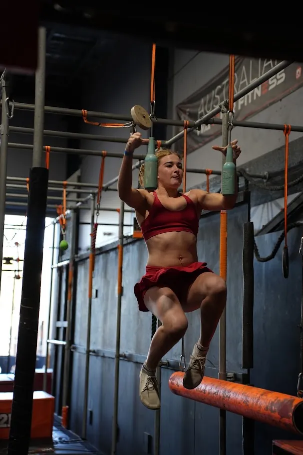 Competitor in red hanging from grips on the AWF ninja rig