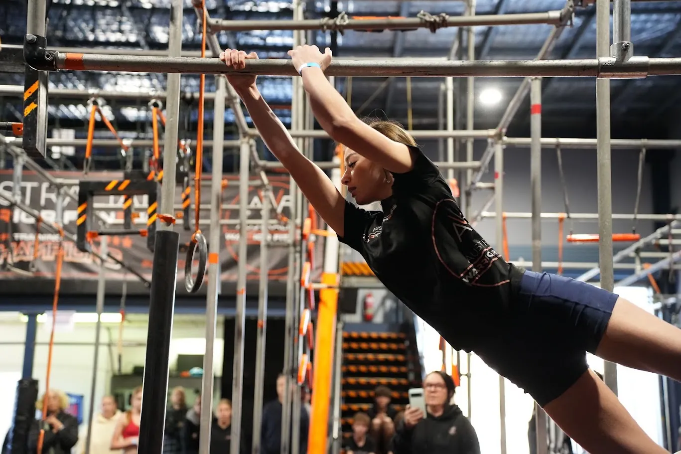 Competitor in black reaching for a bar on the AWF ninja rig
