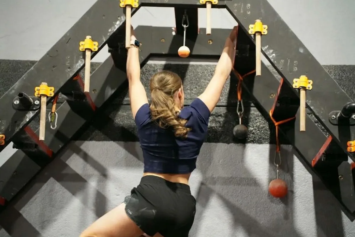 Athlete hanging from the peg board obstacle at AWF Gosford