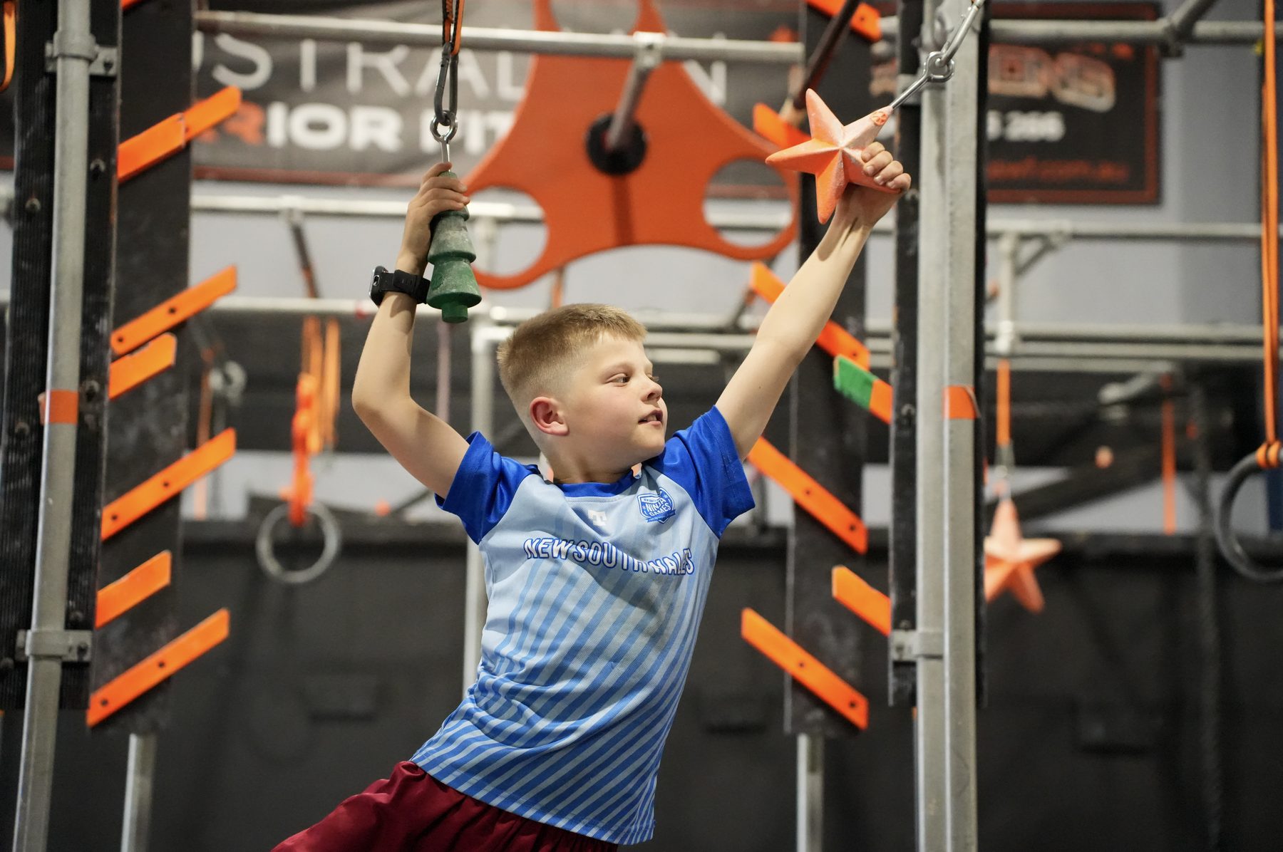 Boy swinging on the rings at an AWF kids ninja party